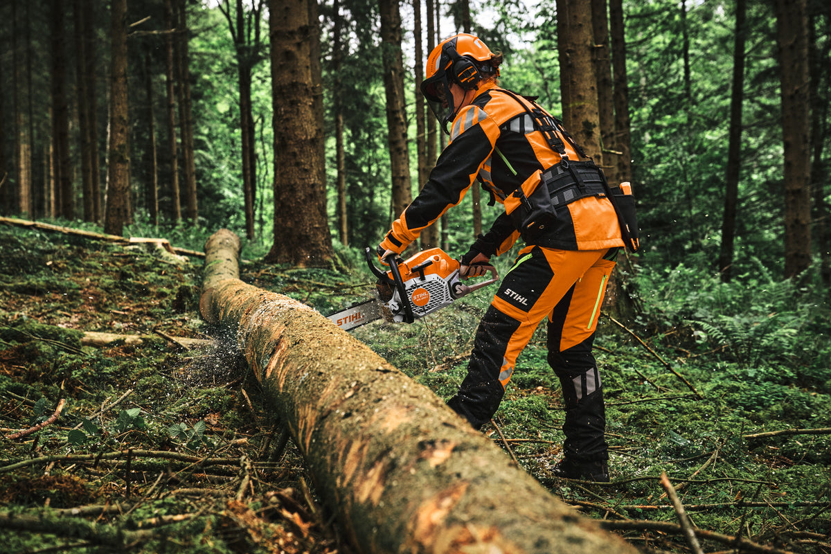 Operatore con motosega STIHL MS 300 C-M durante il taglio di un tronco a terra nel bosco.