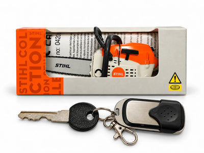Mini motosega STIHL da collezione nella confezione originale affiancata a una chiave con telecomando per mostrare le dimensioni reali del prodotto.