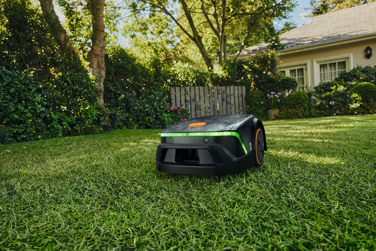 Robot tosaerba Stihl iMOW 4 EVO bagnato su un prato in giardino.