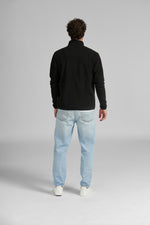 Uomo di spalle con giacca nera in pile e jeans chiari