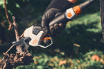 Mano con guanto che impugna la cesoia Stihl ASA 130 vicino a un tralcio