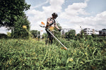 Operatore che utilizza un decespugliatore in un'area con vegetazione alta.