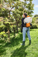 Persona con irroratore dorsale Stihl SGA 60 mentre nebulizza su un albero.