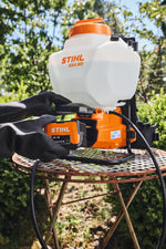 Irroratore Stihl SGA 60 su tavolo da giardino durante l'inserimento della batteria.