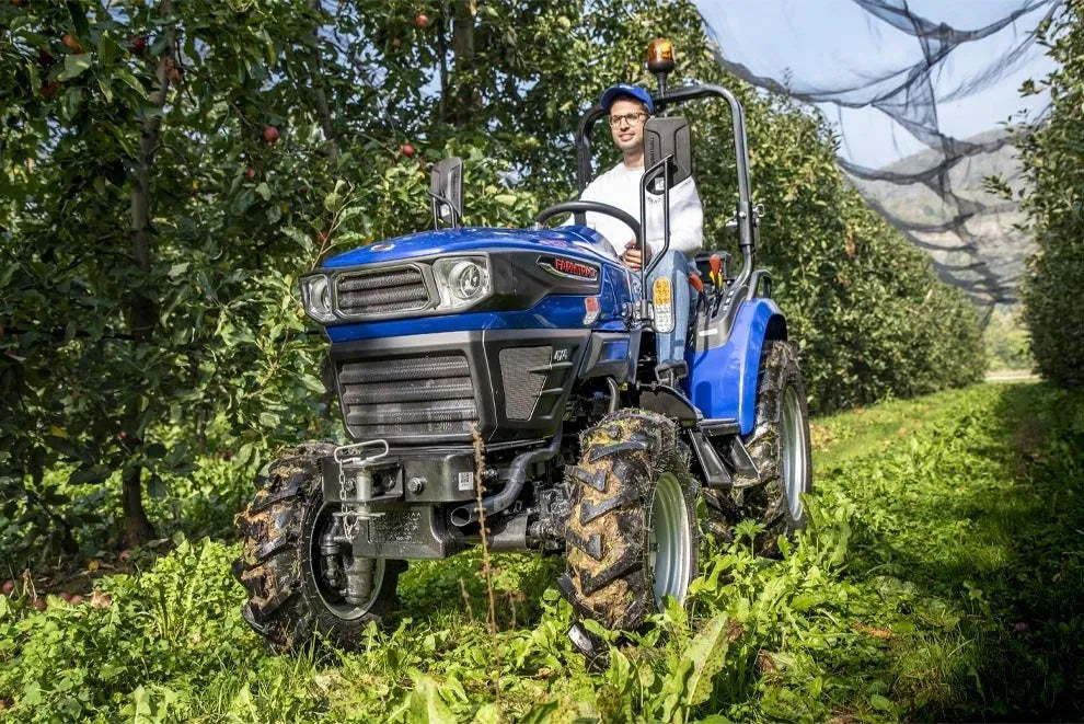 Trattore compatto Farmtrac 4RM vista anteriore in frutteto