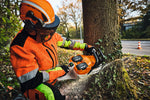 Operatore con motosega a due batterie taglia la base di un albero